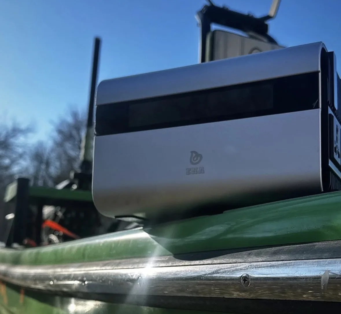 An ENA POPS portable power station strapped to the deck rail of a small boat under a clear sky
